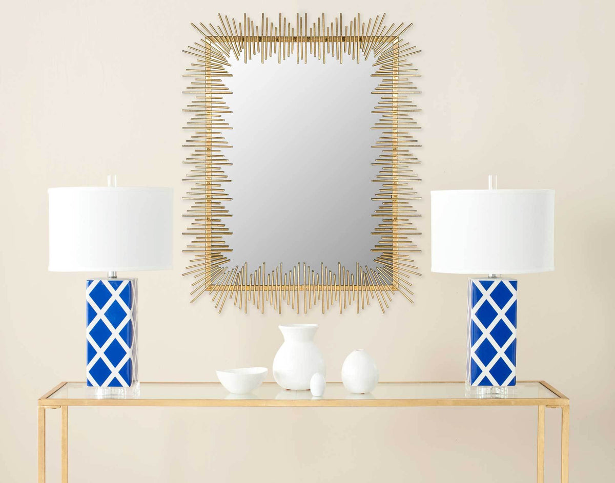 A rectangular gold mirror brightens the wall above a console flanked by blue lamps.