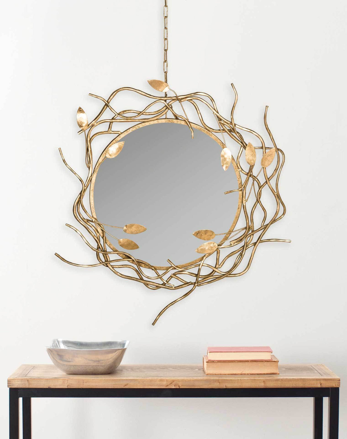 A sculptural gold leaf-and-branch mirror adds warmth and character above a console