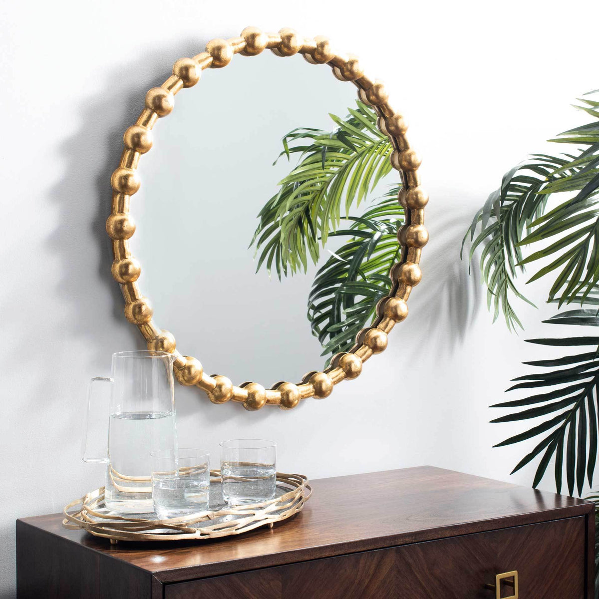 A gold-beaded mirror brings warmth and sparkle to the wall above a wood console.
