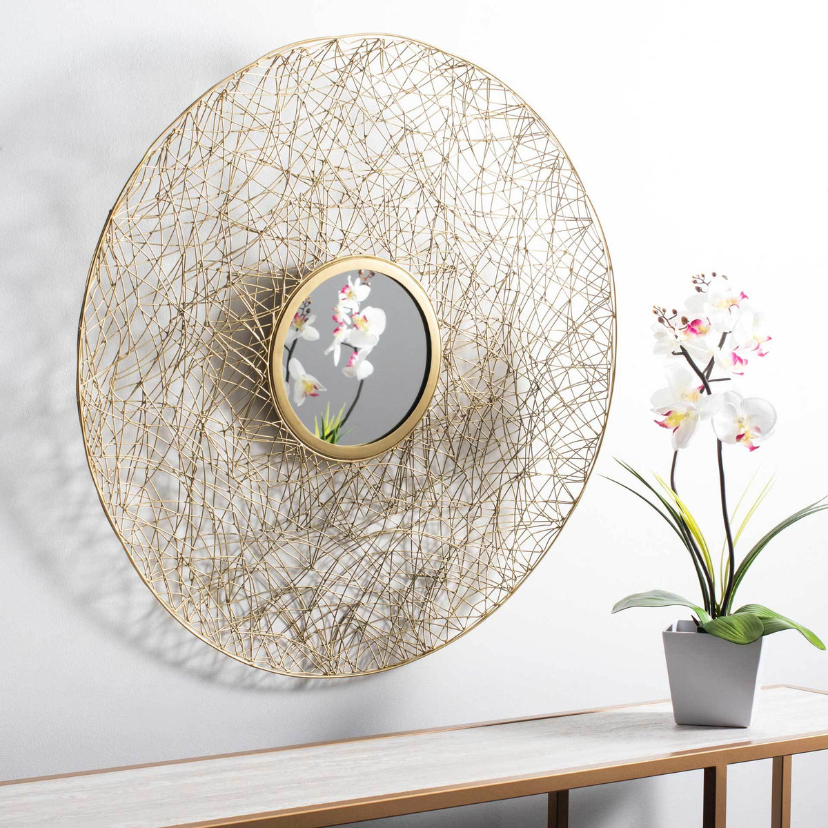 Brass wire mirror adds warm texture and sculptural appeal above a console table