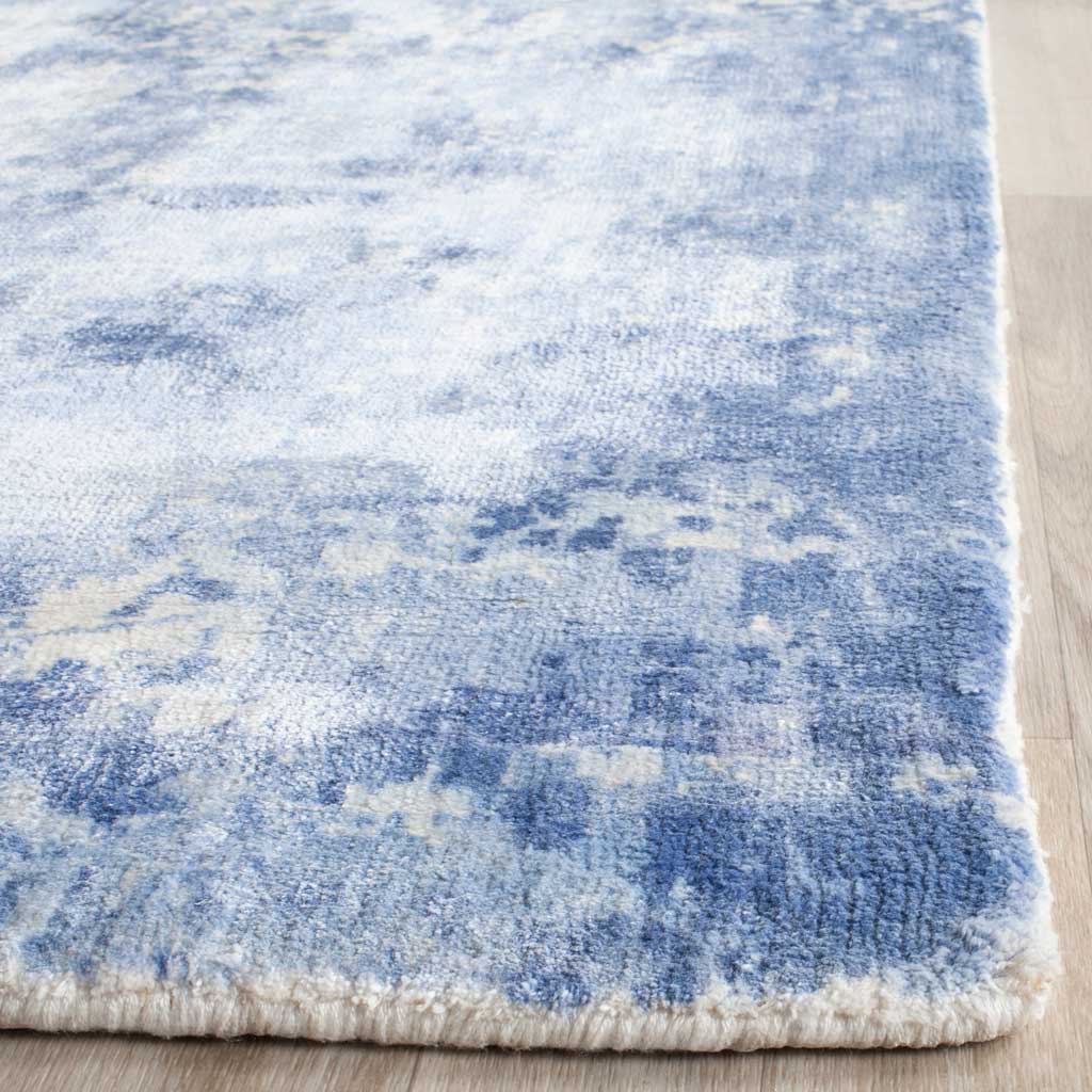 A neatly finished edge borders the rug's softly textured blue-and-ivory pile