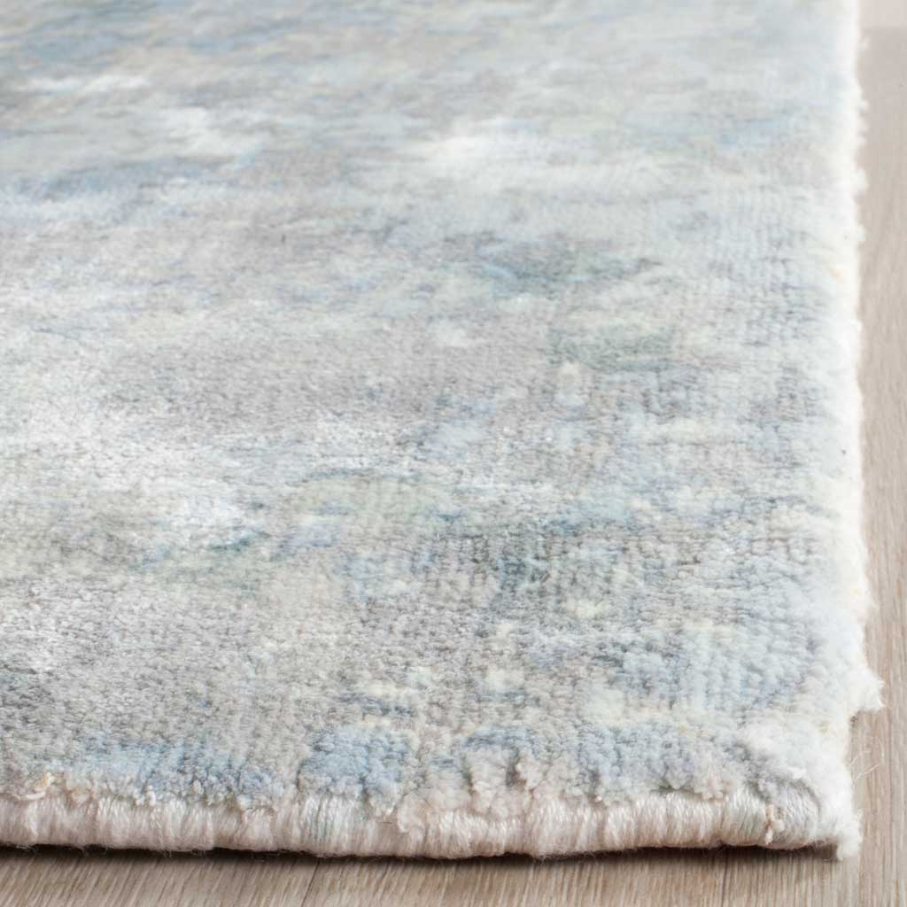 A neatly finished edge frames the rug's soft pile and layered aqua and ivory tones.