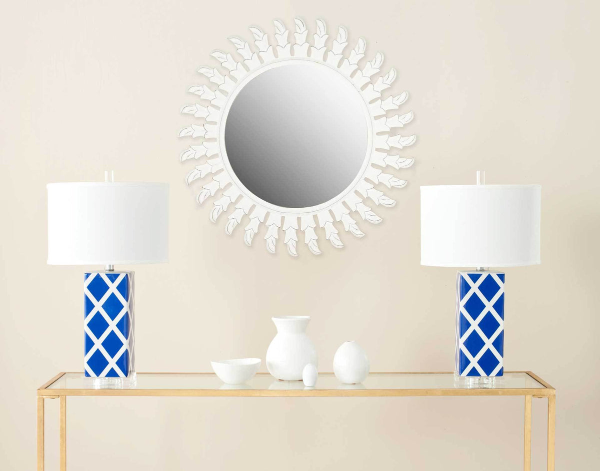 A round mirror with white leaf-inspired rays brings an airy accent to the wall.