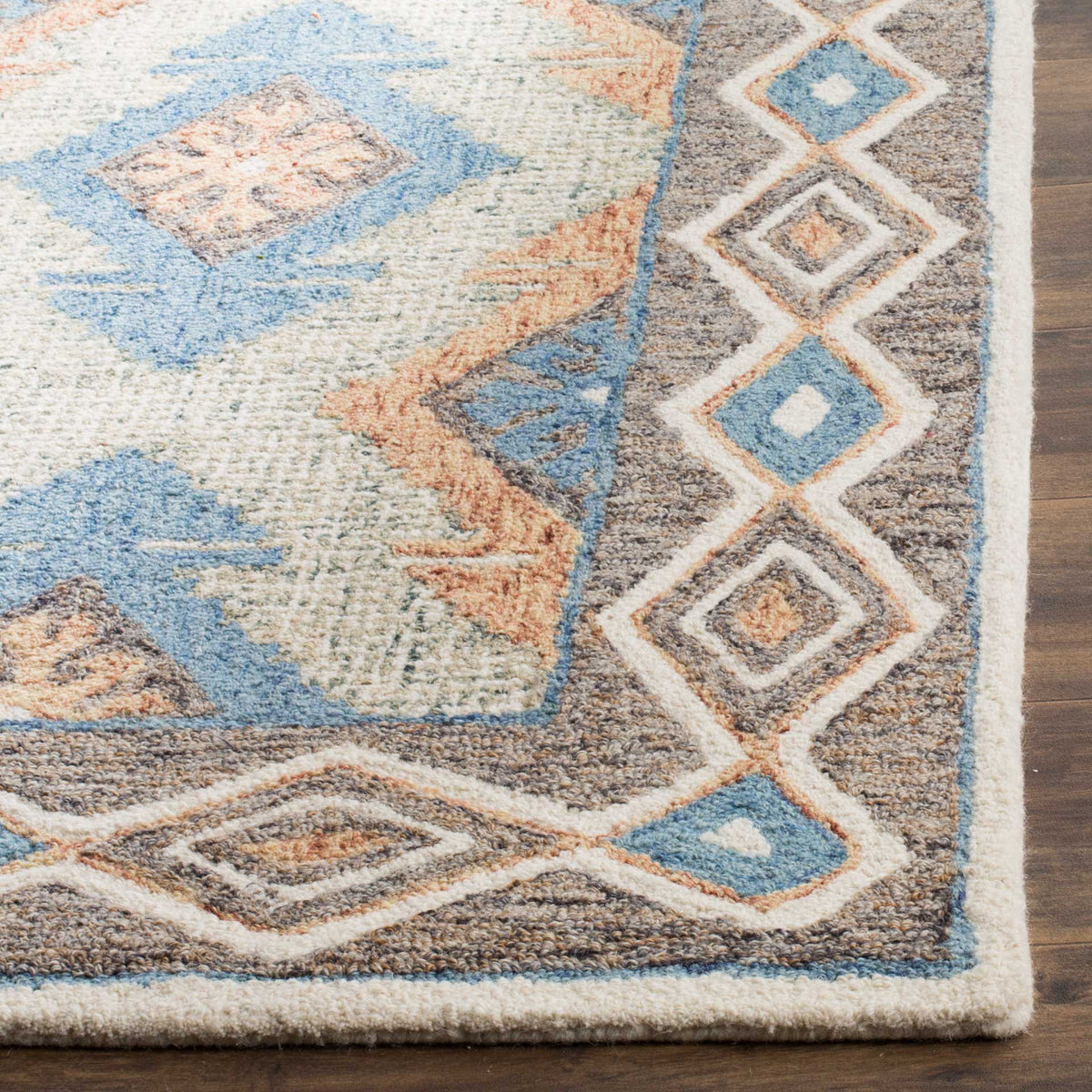 Soft wool pile and a neatly finished edge accent the rug's layered blue and rust diamond border.