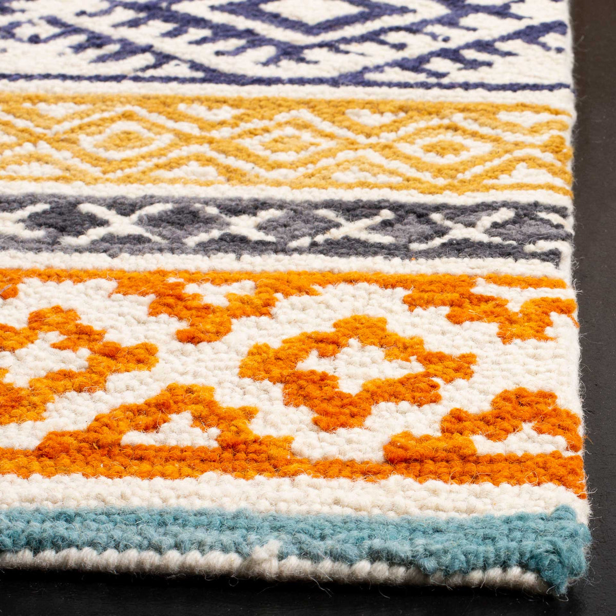 Plush tufted loops highlight orange geometric motifs, gold detailing and a teal-edged finish
