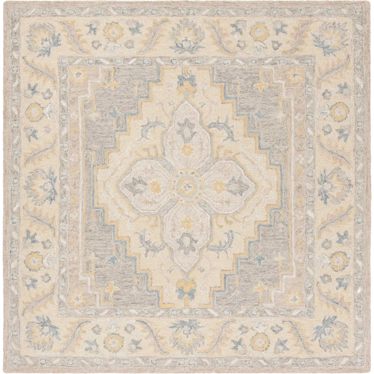 A square wool rug features a central floral medallion and scrolling border in soft beige, gray, and blue.