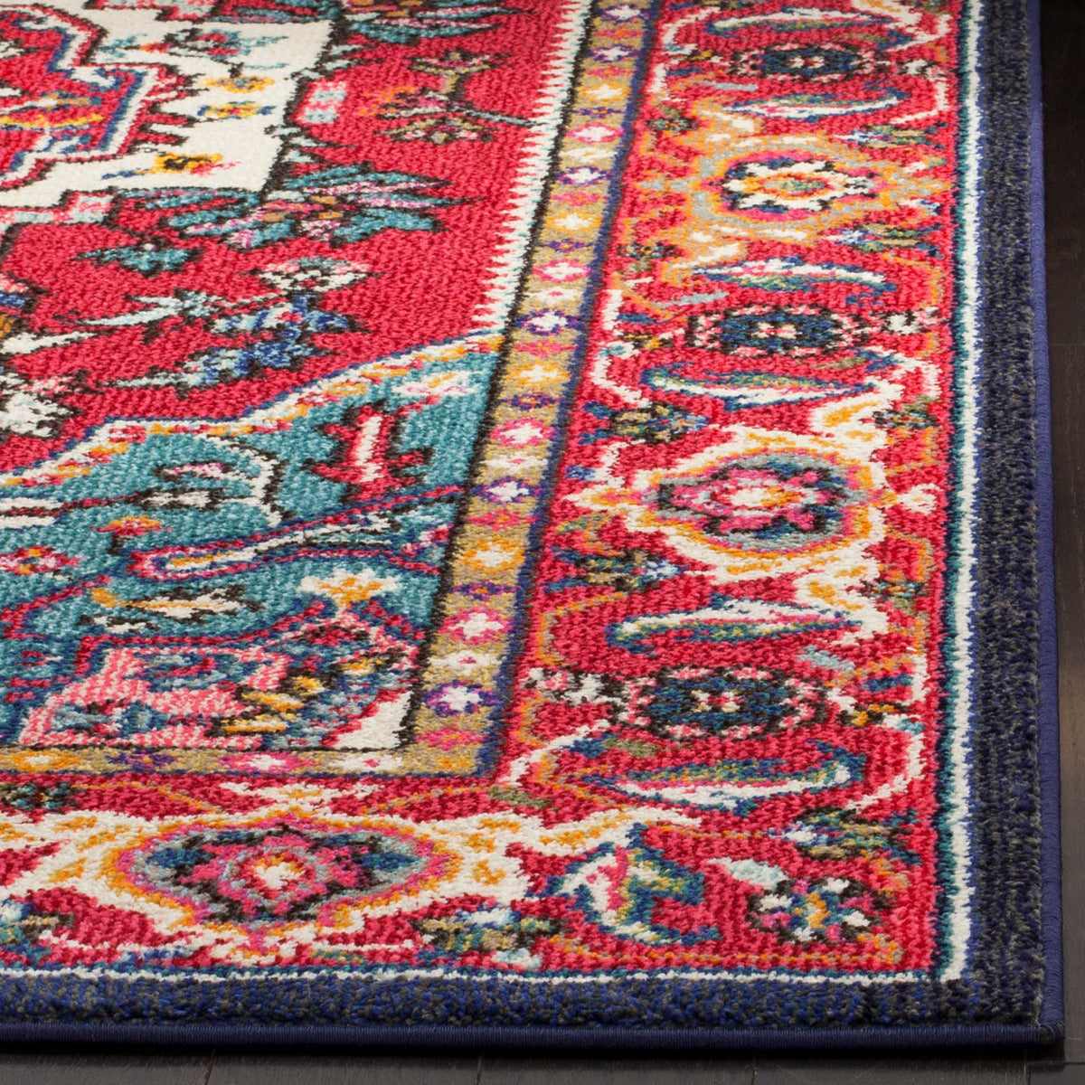 Vivid red and turquoise blossoms fill the textured border of a rug with a narrow navy edge.