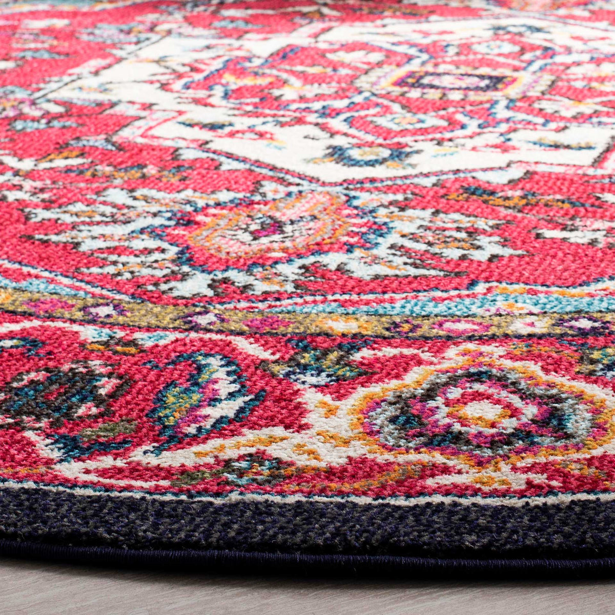 Textured floral motifs in red and turquoise meet the rug's neatly finished navy edge