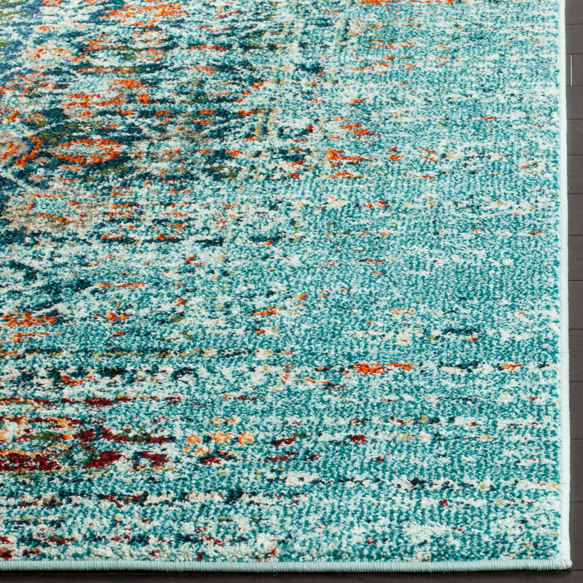 Turquoise rug corner shows a neatly bound edge and scattered rust and navy accents