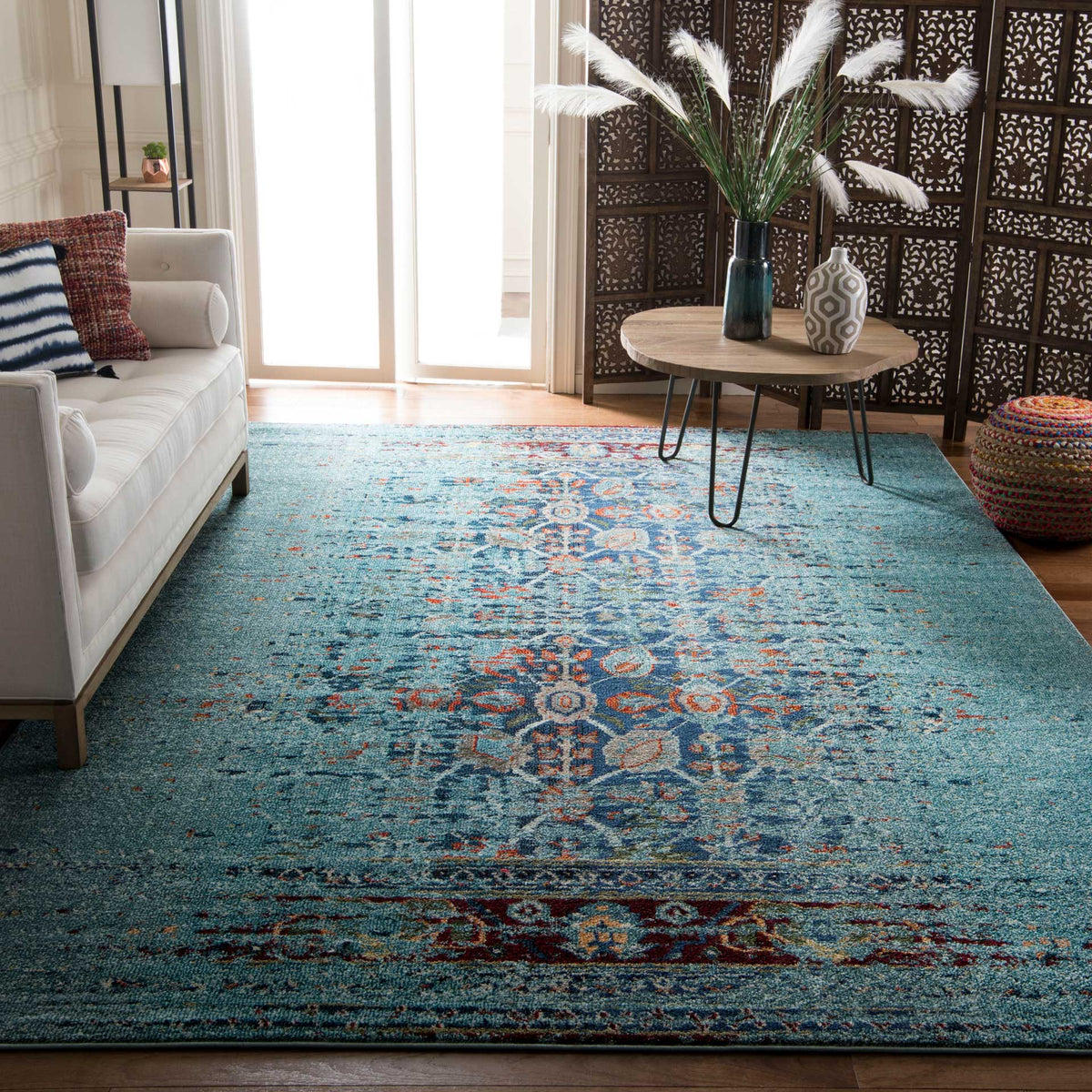 Distressed turquoise rug grounds the living room with vivid floral motifs and warm accents