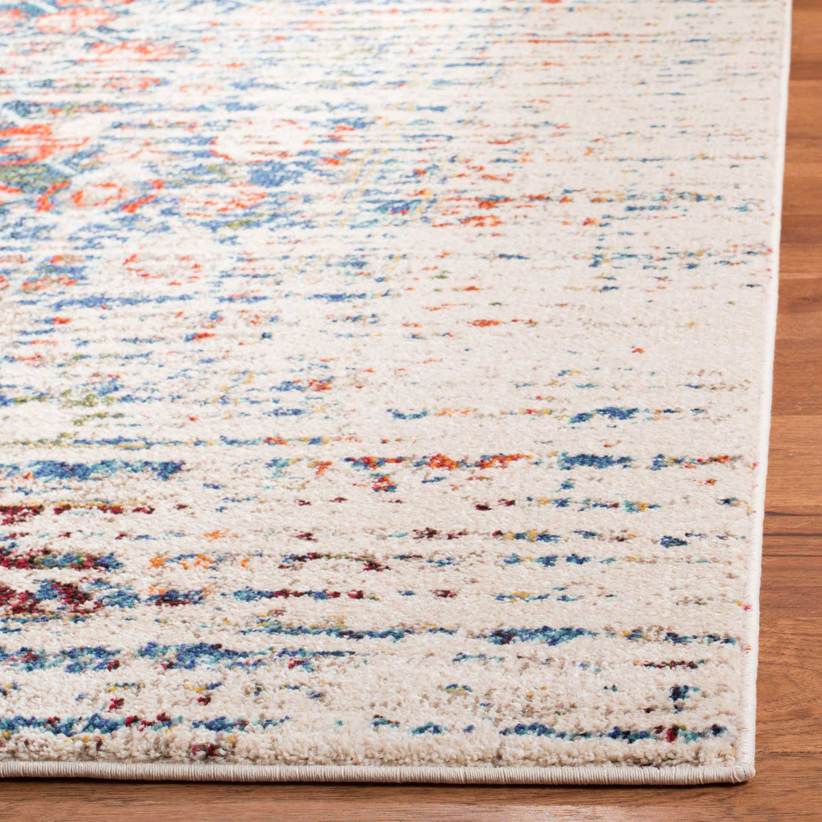 Ivory rug corner shows textured pile and softly worn blue and orange motifs