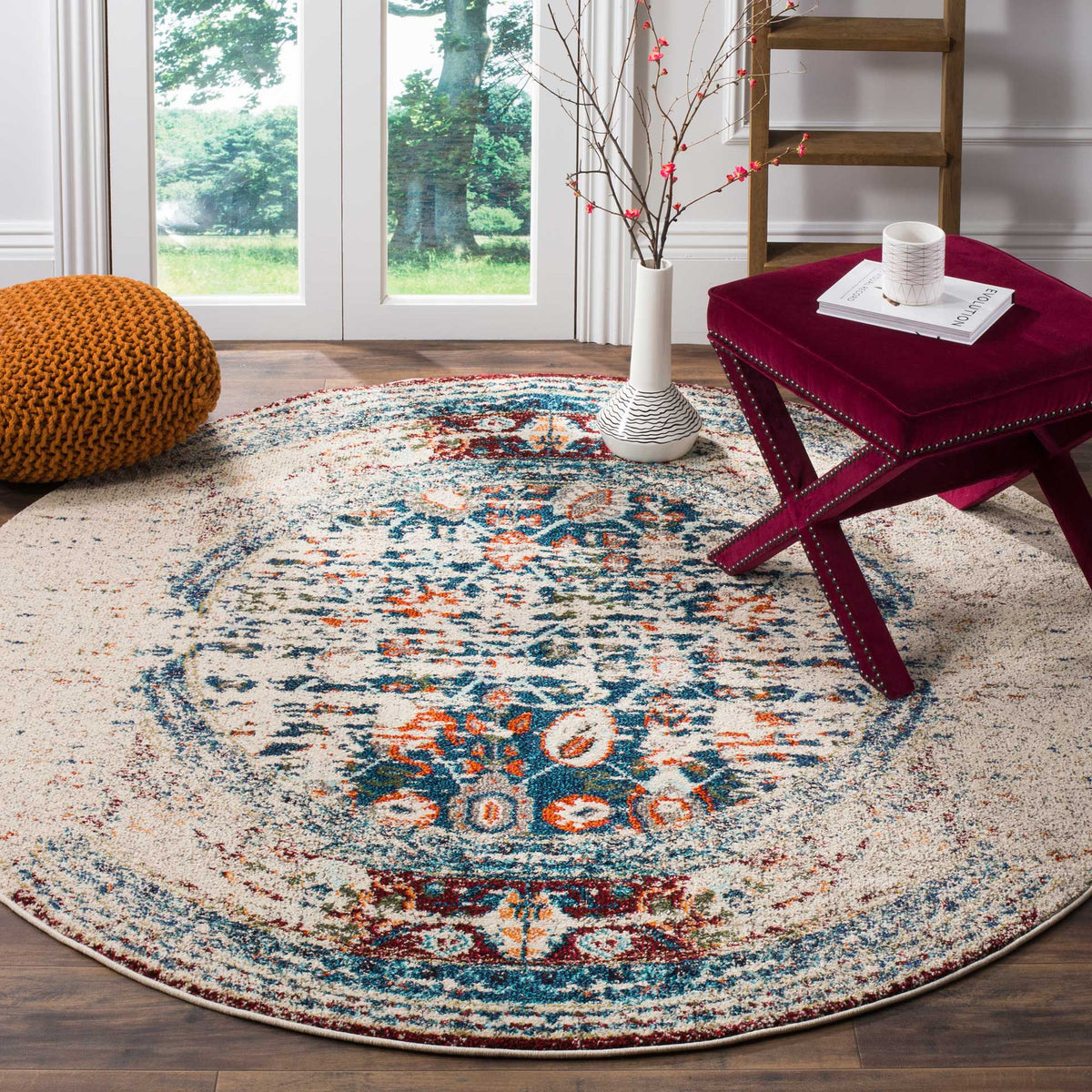 An ivory round rug grounds the room with an ornate blue medallion and softly distressed details
