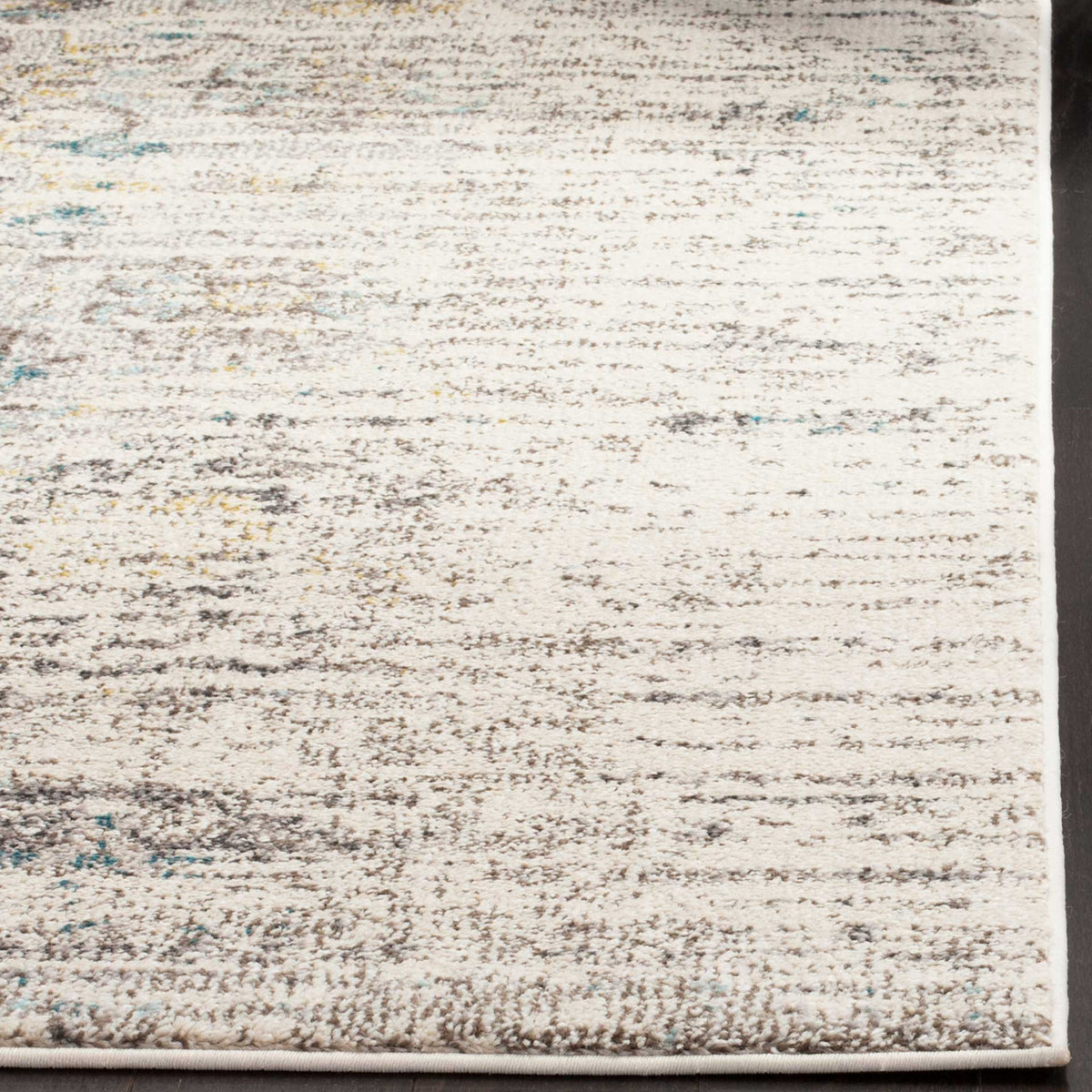 Faded gray and ivory fibers with blue and gold flecks meet at a neatly bound corner