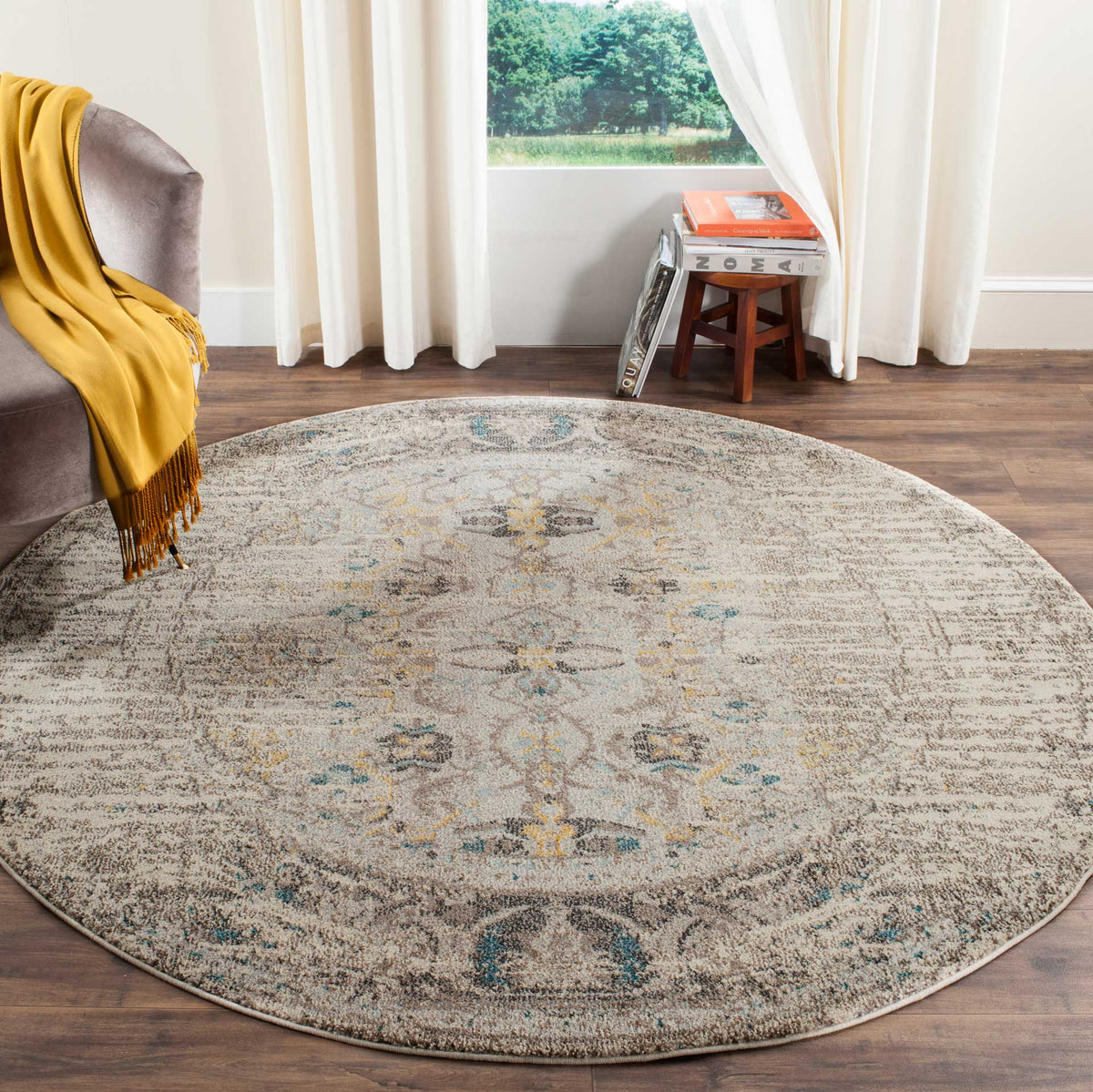 Soft gray round rug brings faded floral motifs and subtle teal accents to the floor.
