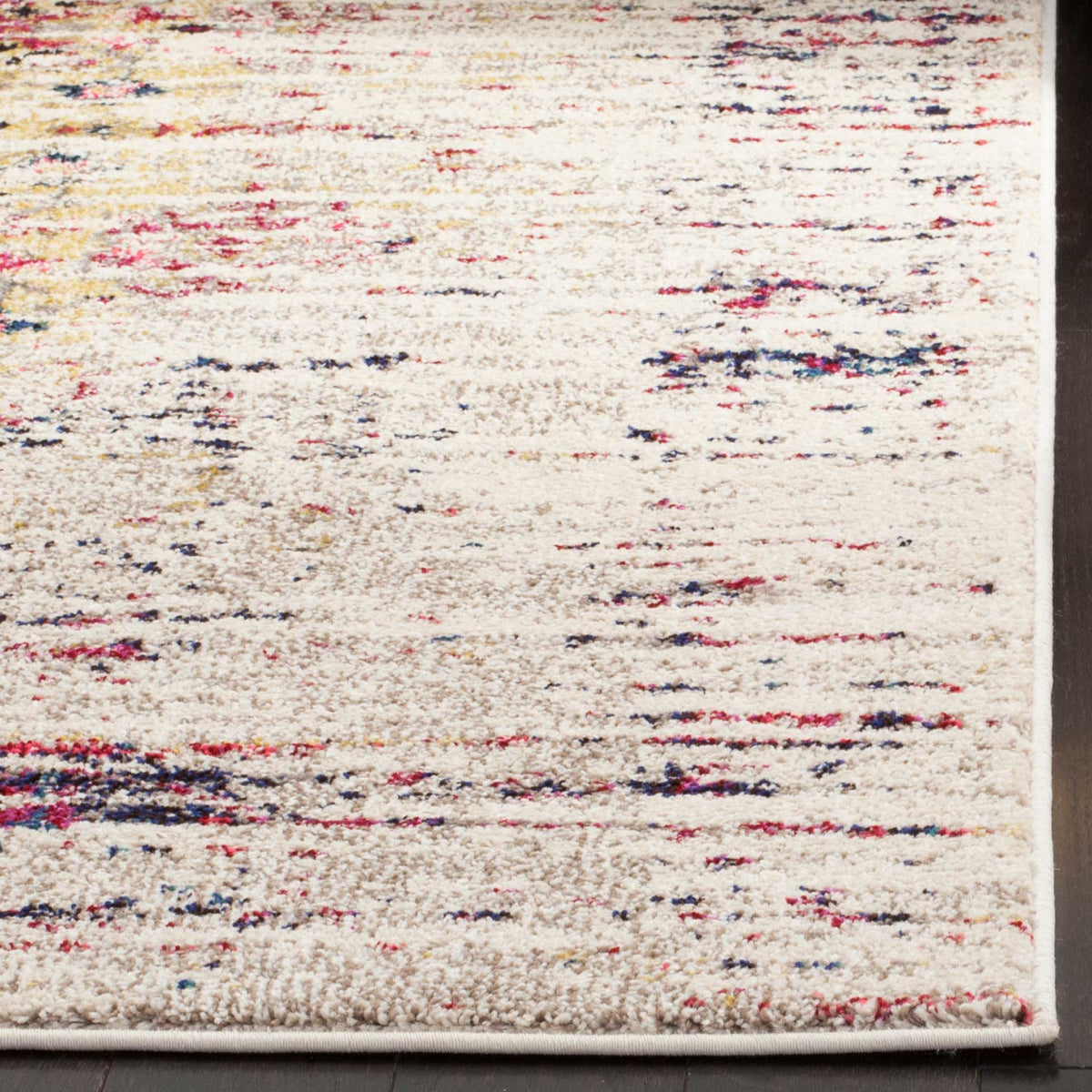 An ivory rug corner reveals plush texture and distressed pink and navy flecks along the bound edge