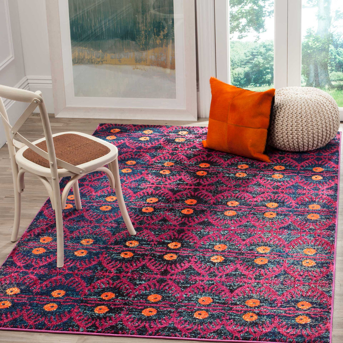 Pink flourishes and orange accents bring lively color beneath a white chair and soft floor pillows.