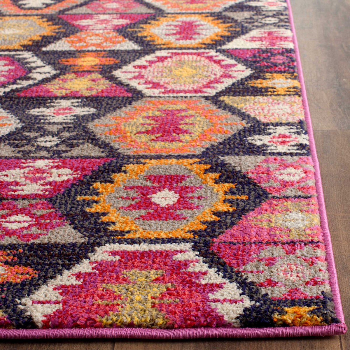A neatly bound pink edge frames colorful geometric motifs and textured pile