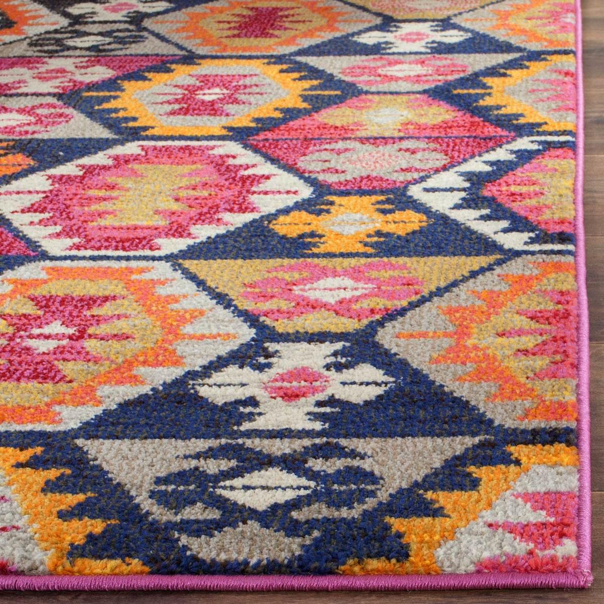Bright geometric shapes meet a neatly bound pink edge over a textured, low-profile pile.