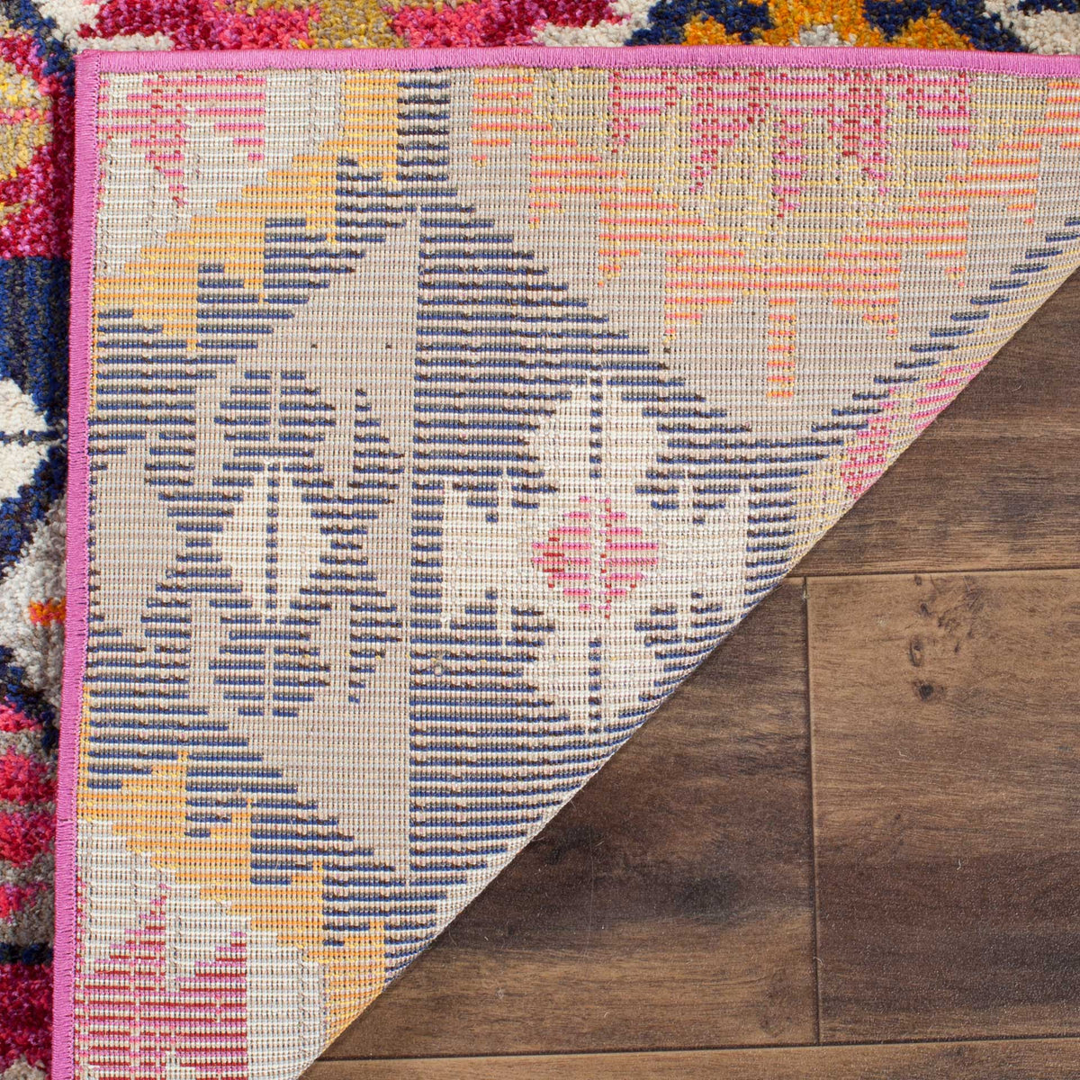 Pink binding frames the woven underside of this vibrantly patterned area rug.