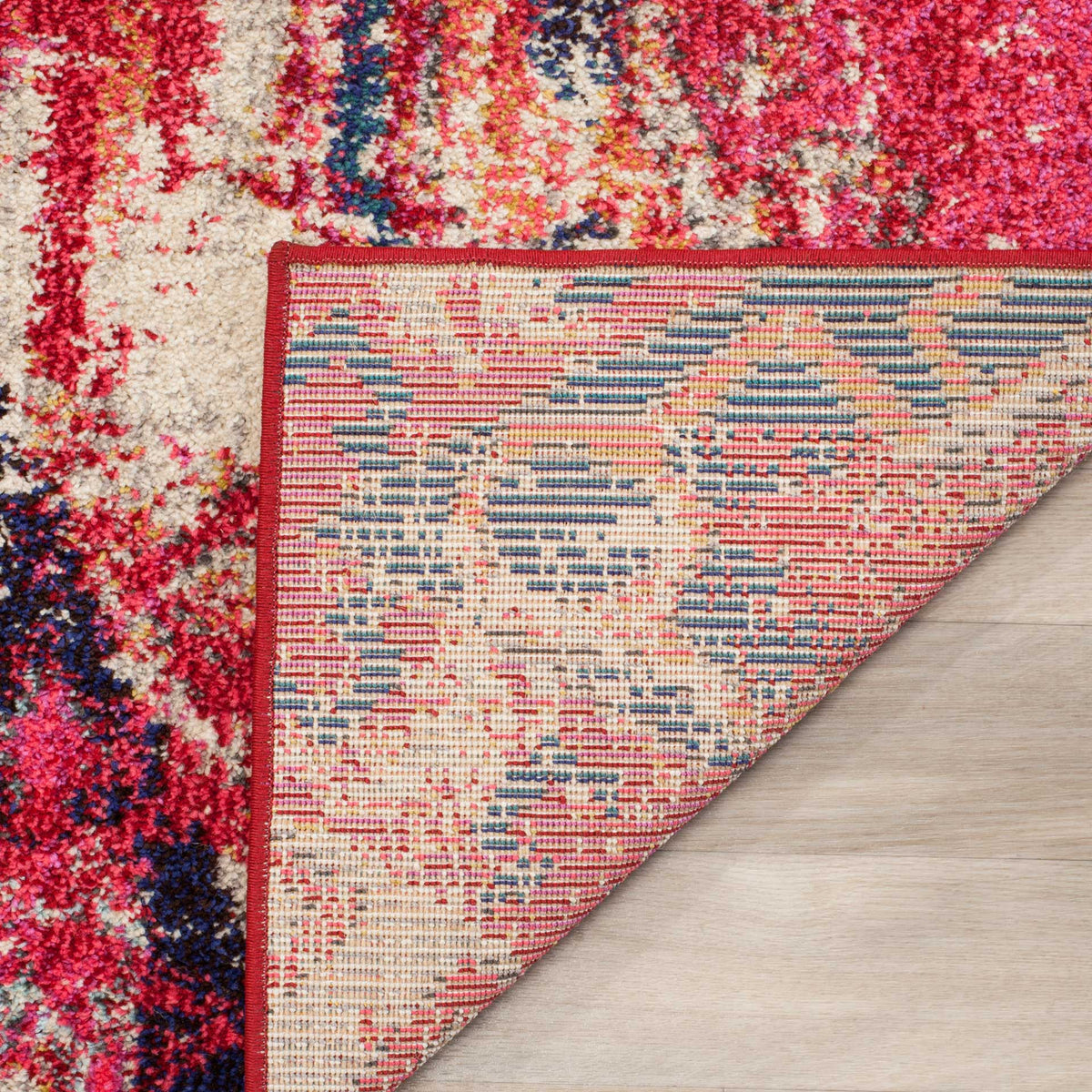 A folded corner reveals woven backing beneath bright magenta and cream patterns
