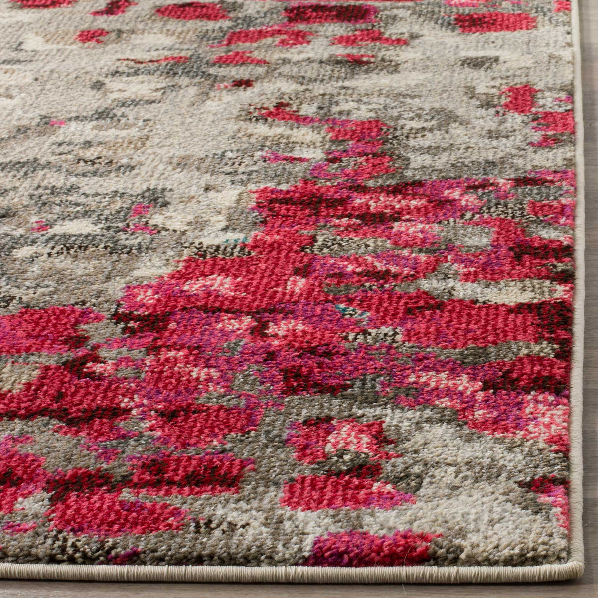 Bright fuchsia and gray yarns create a plush abstract pile finished with neat binding