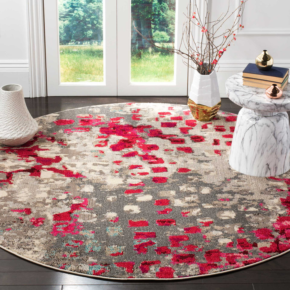 Fuchsia accents brighten a round gray rug with a weathered abstract pattern on dark wood floors