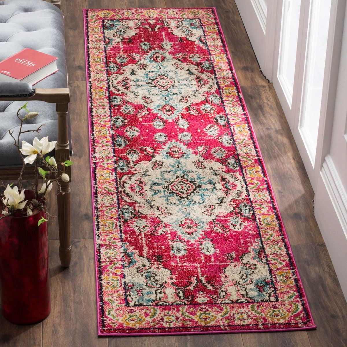 Bold pink runner adds vibrant medallions and floral detail beside a gray tufted chair