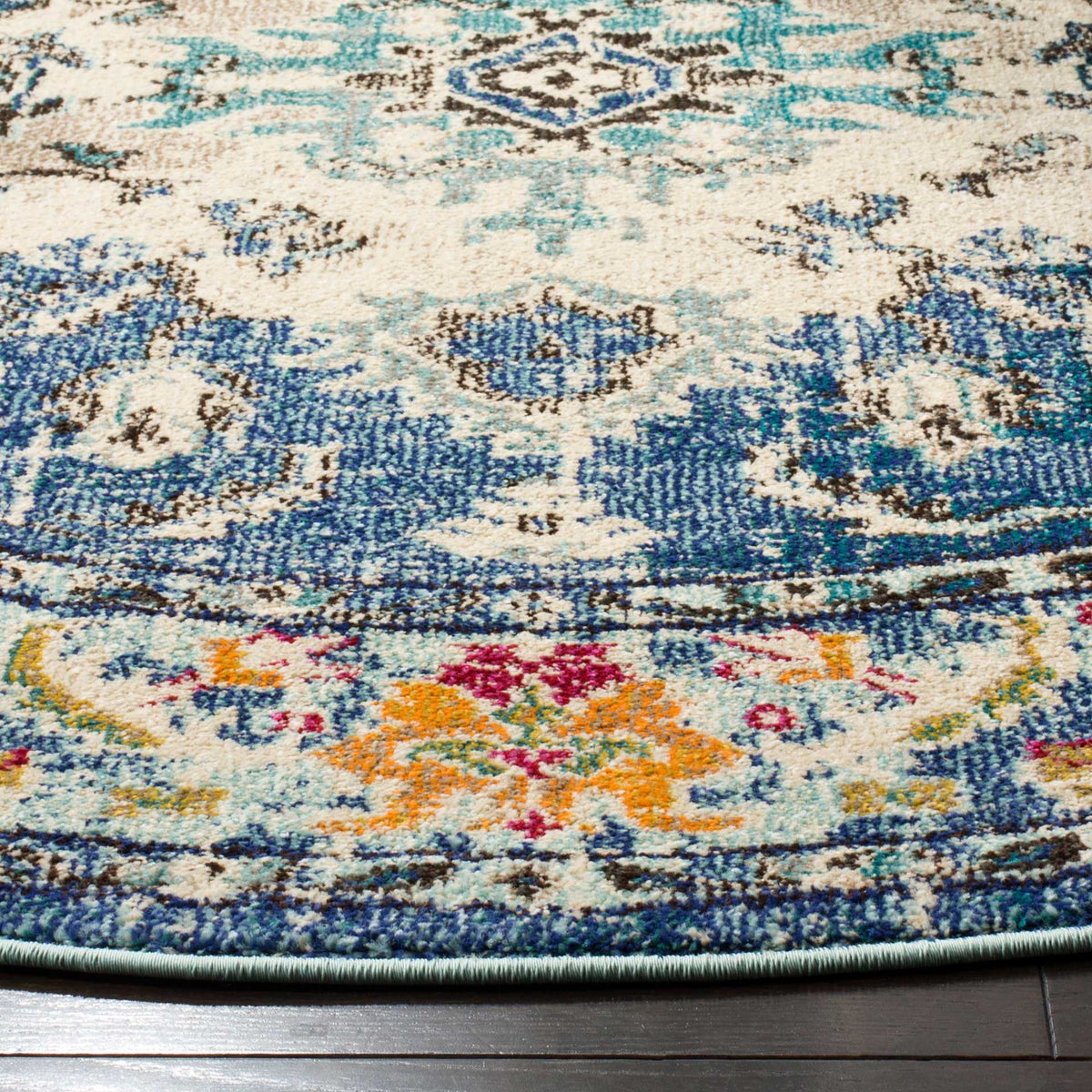 Navy and pale blue scrolls meet orange and pink blooms near the rug's neatly bound edge
