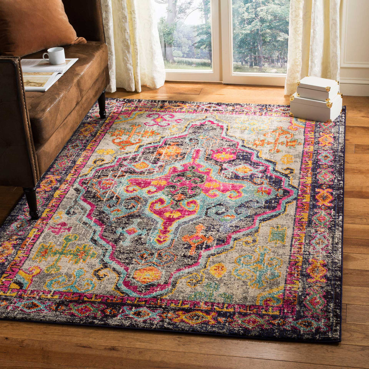 A gray rug with a bright fuchsia medallion and multicolored border enlivens a cozy living room.