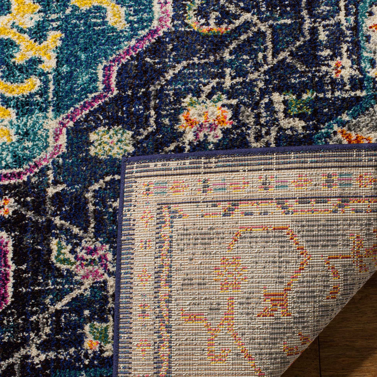 Folded rug corner reveals woven backing beneath the vivid blue and turquoise patterned pile