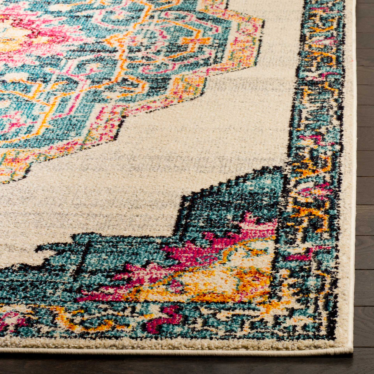 Bright teal, pink, and orange motifs decorate the cream rug's patterned corner and bound edge.