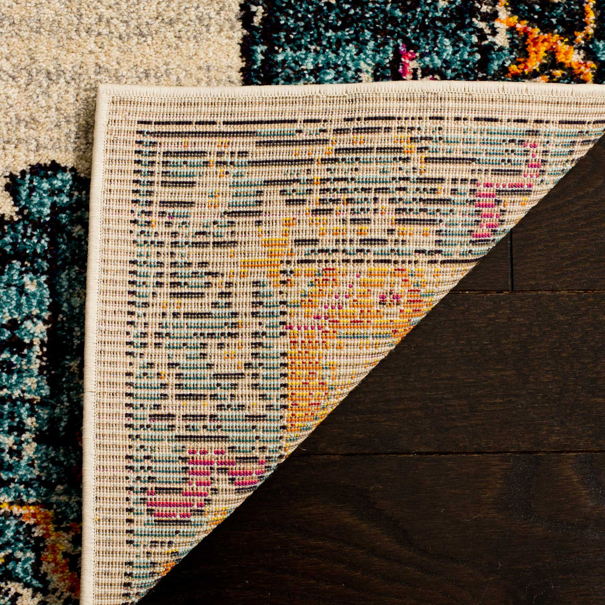 Woven cotton backing and a neatly bound edge lie beneath the colorful cream-and-teal pile.