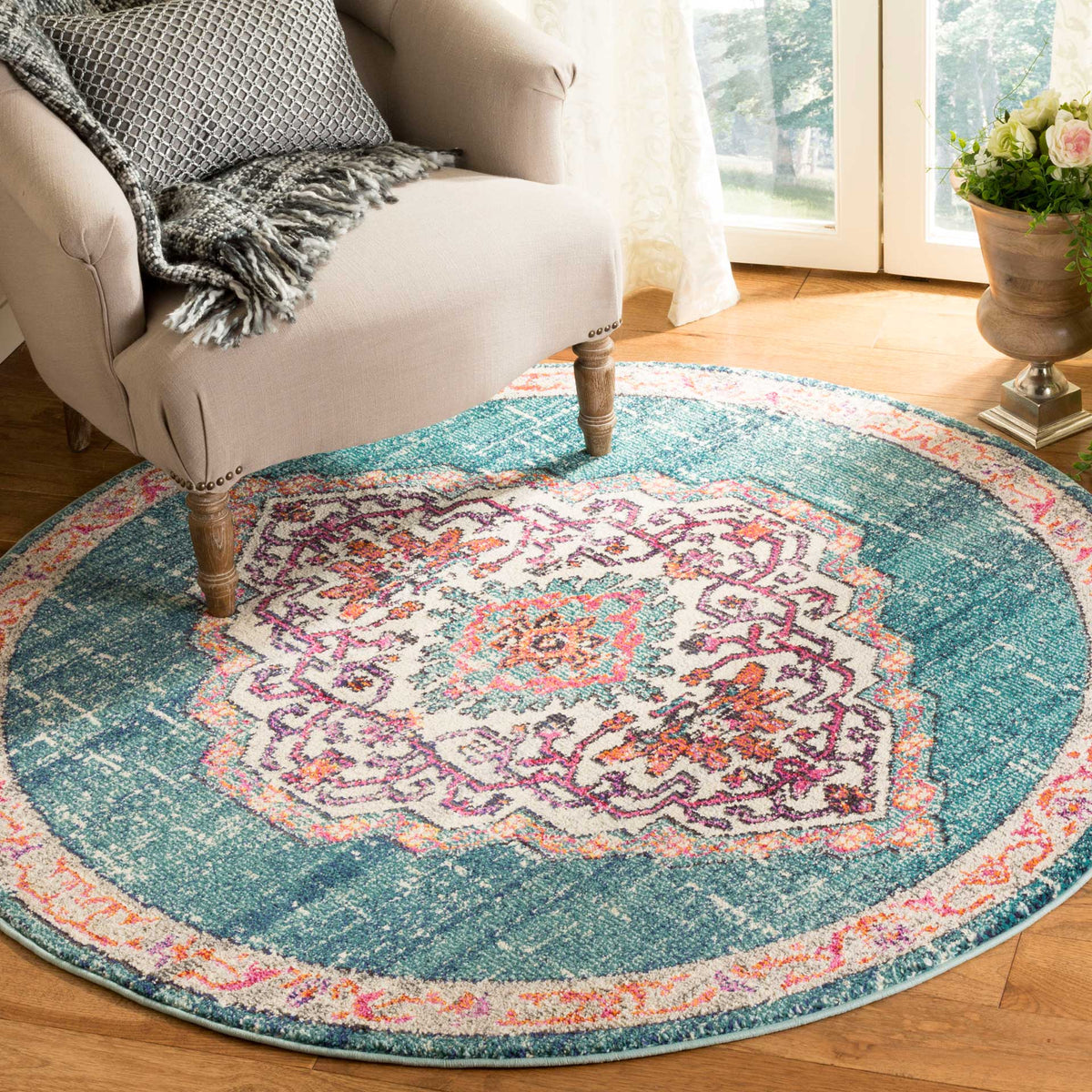 Intricate multicolor motifs bring warmth and contrast to this teal-blue round rug on a wood floor.