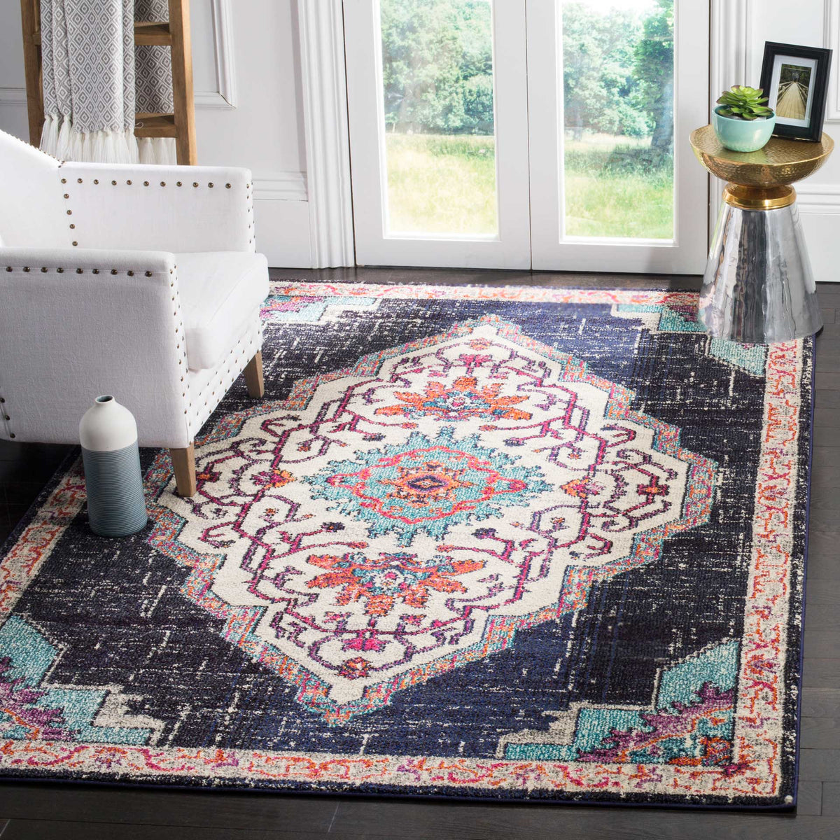 A black and blue rug with a cream floral medallion adds vivid color beneath a white armchair.