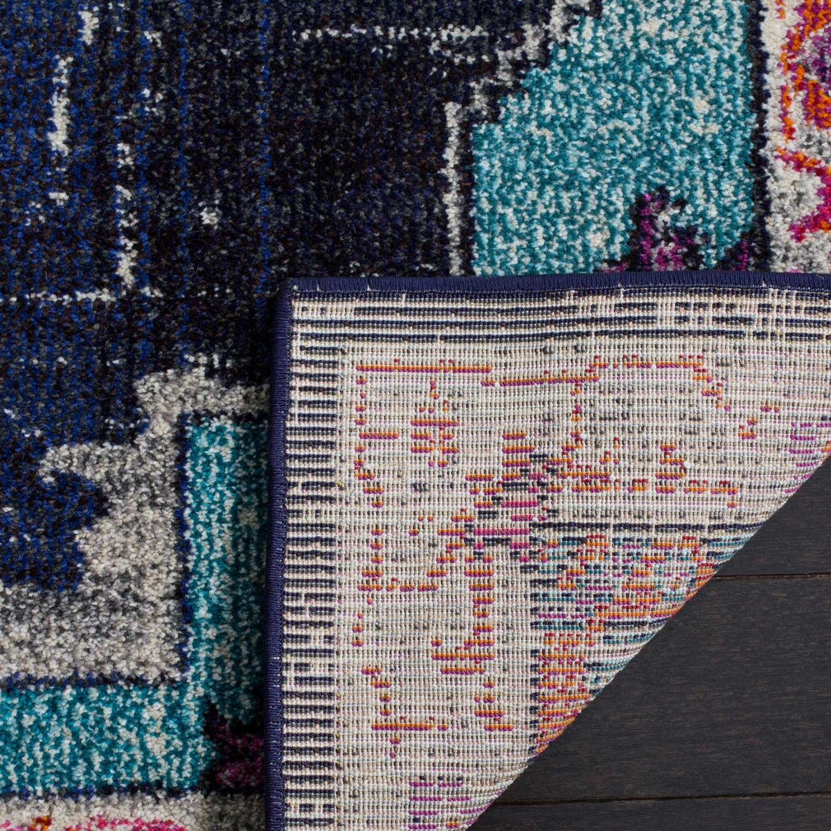 Woven cotton backing and a dark bound edge complement the blue and turquoise patterned pile.