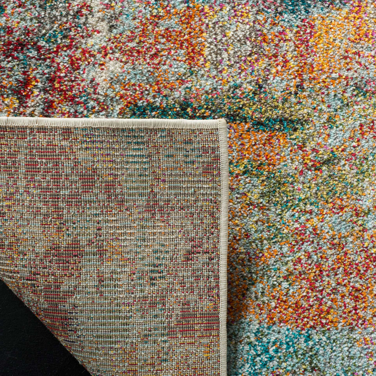 A turned corner reveals woven cotton backing beneath the rug's richly colored pile