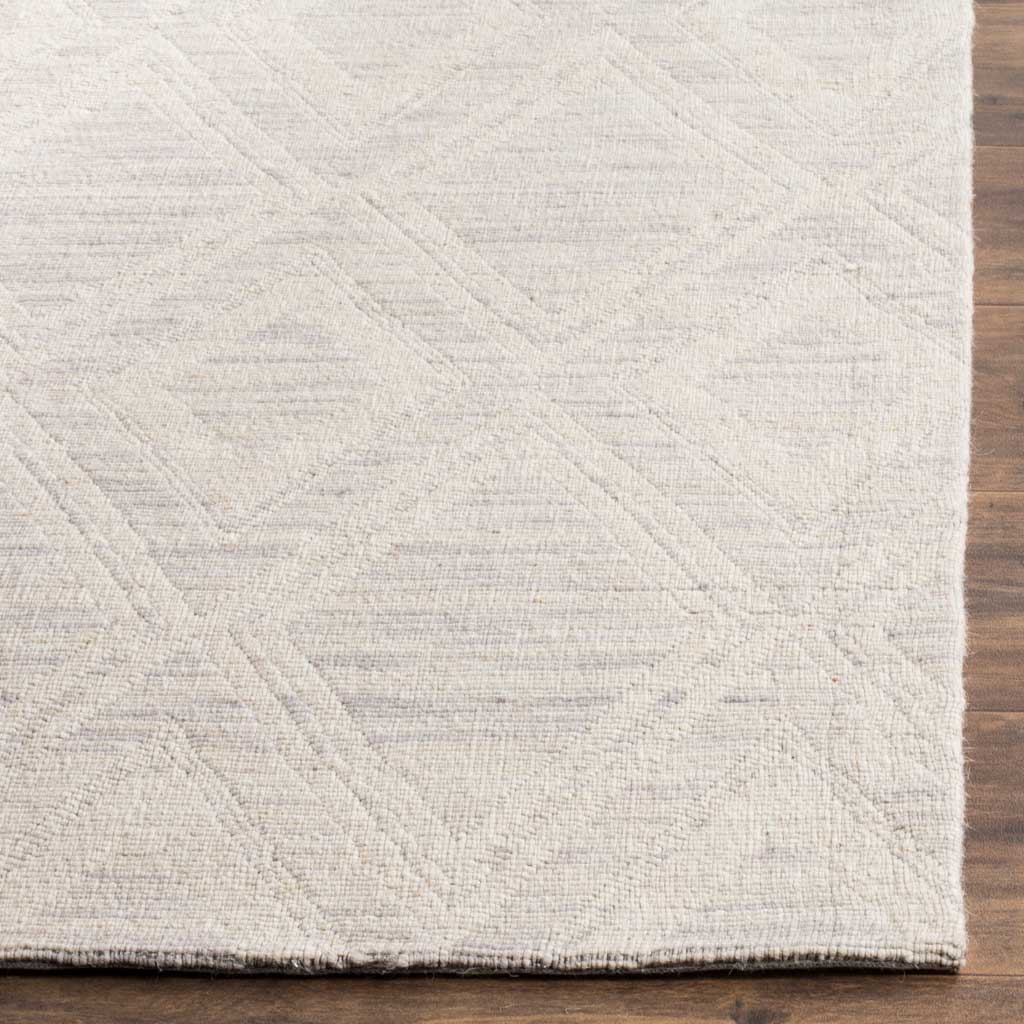 Subtle silver and ivory diamond lines meet a neatly finished edge on this low-profile rug.