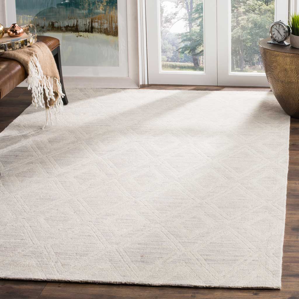 A silver and ivory diamond rug adds quiet texture to a sunlit space with warm wood floors.