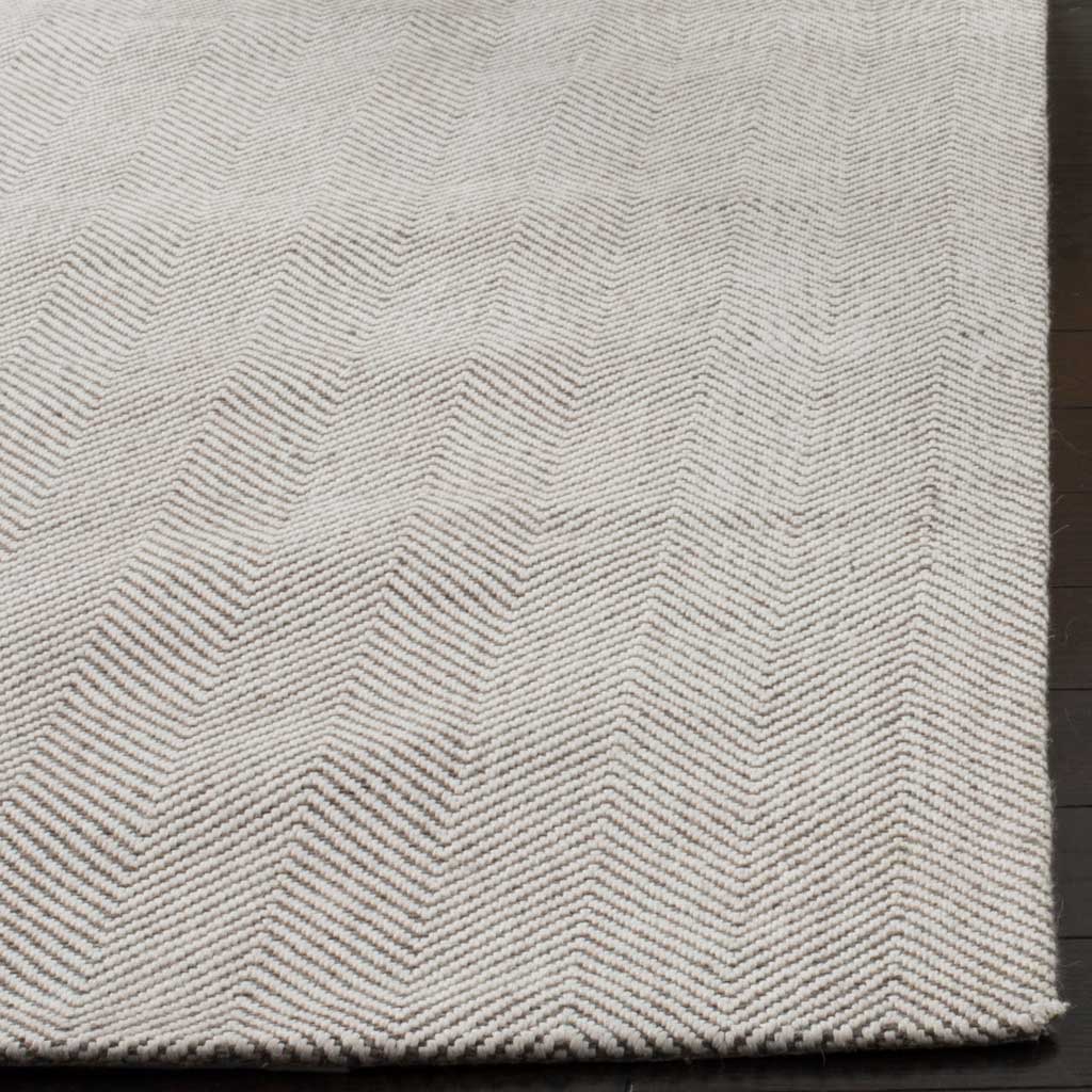 Tightly woven chevrons and a clean edge add definition to the rug's pale silver surface.