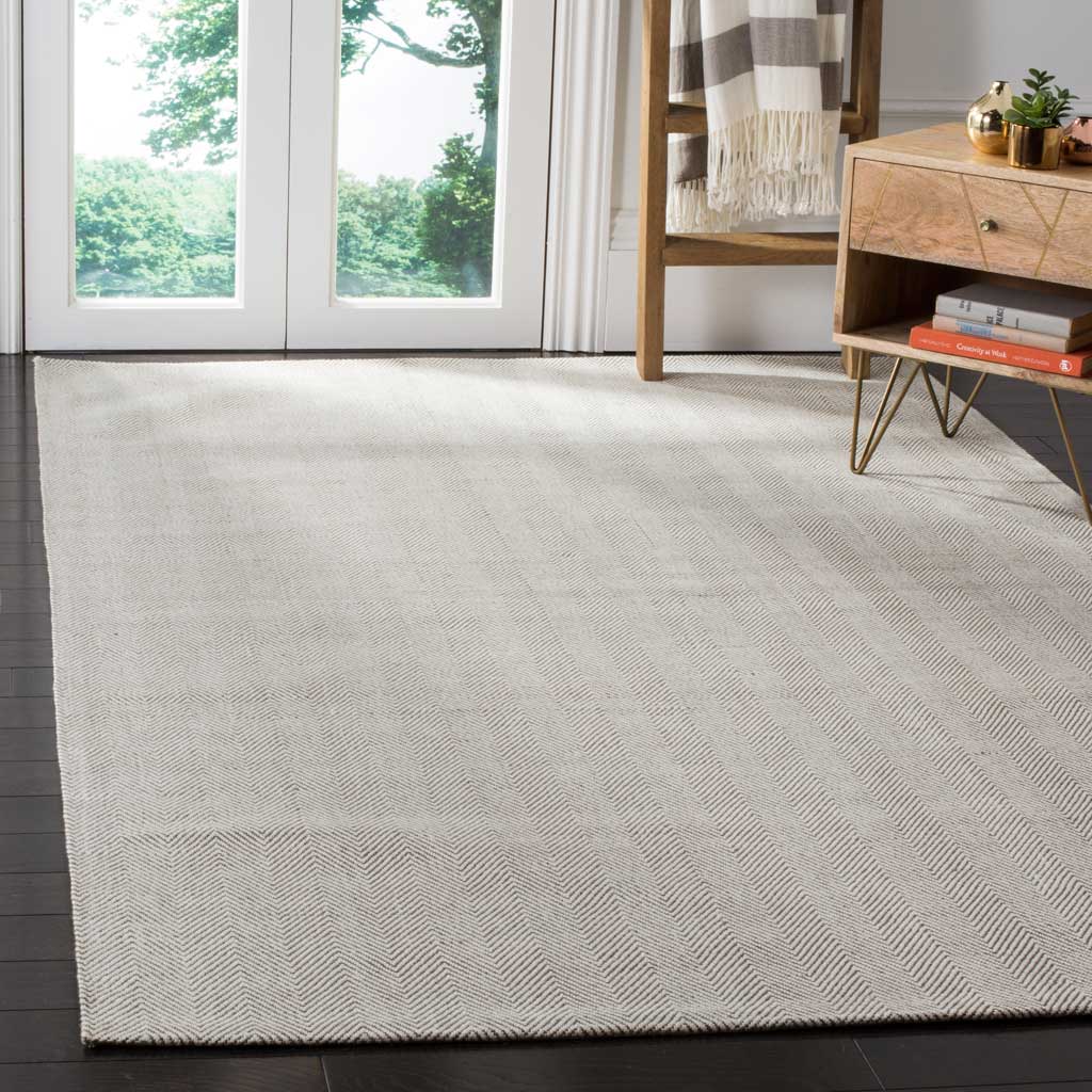A silver chevron rug adds softly patterned texture beneath warm wood furnishings.