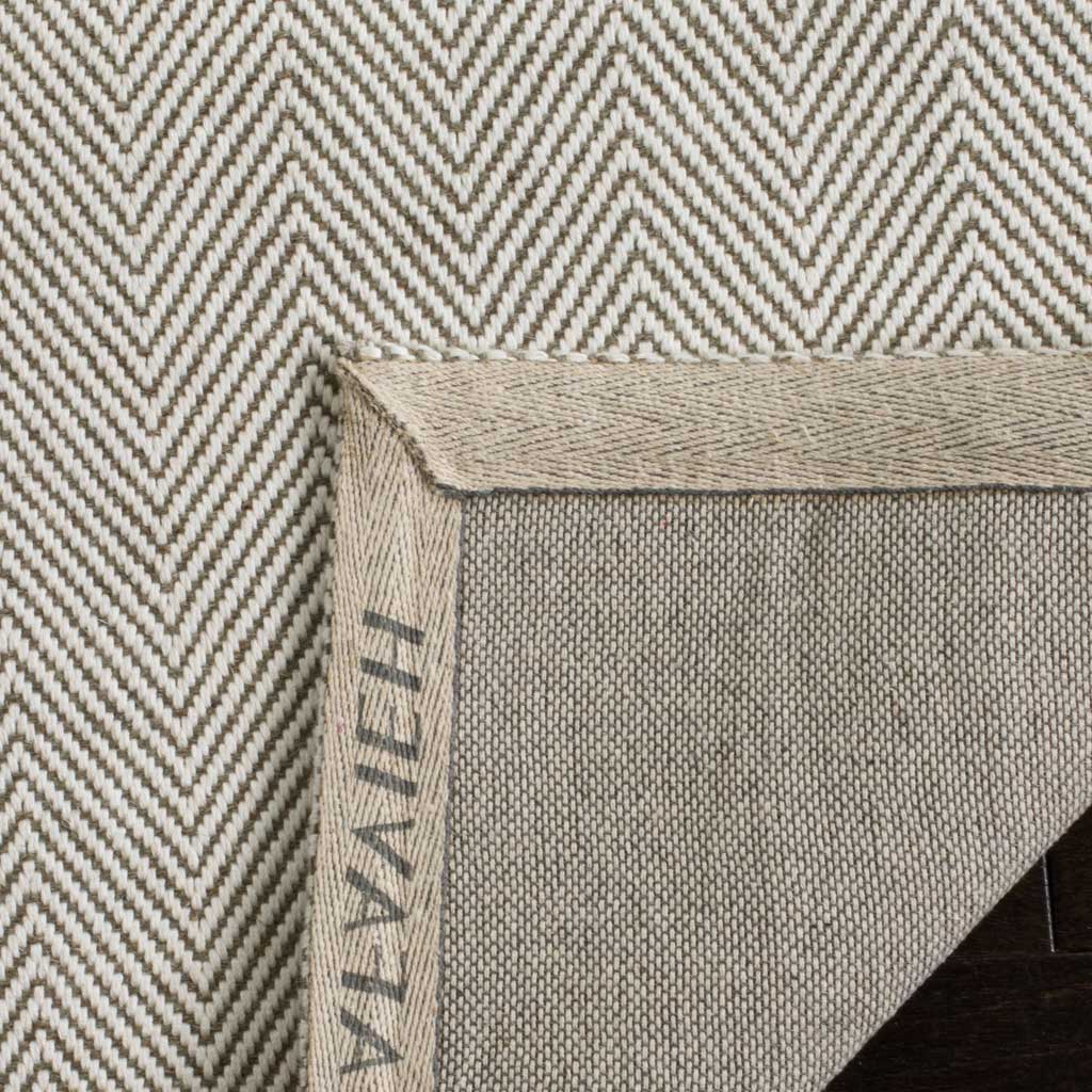 A turned corner reveals the rug's woven backing and carefully finished edge.