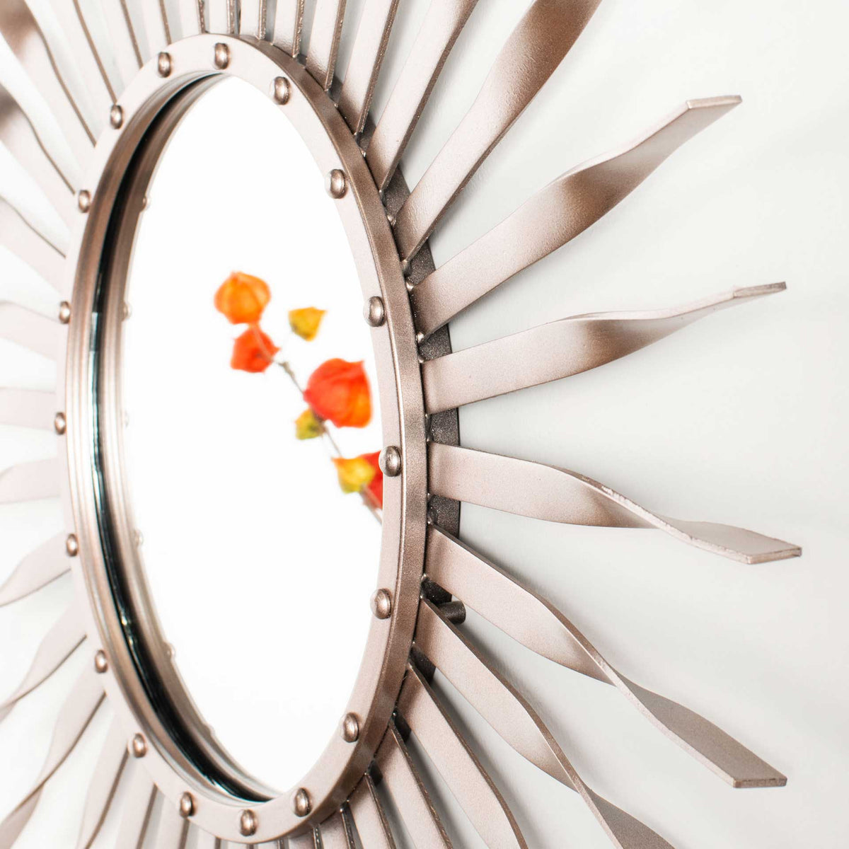 Dimensional rose gold rays and raised studs add sculptural detail around the reflective glass