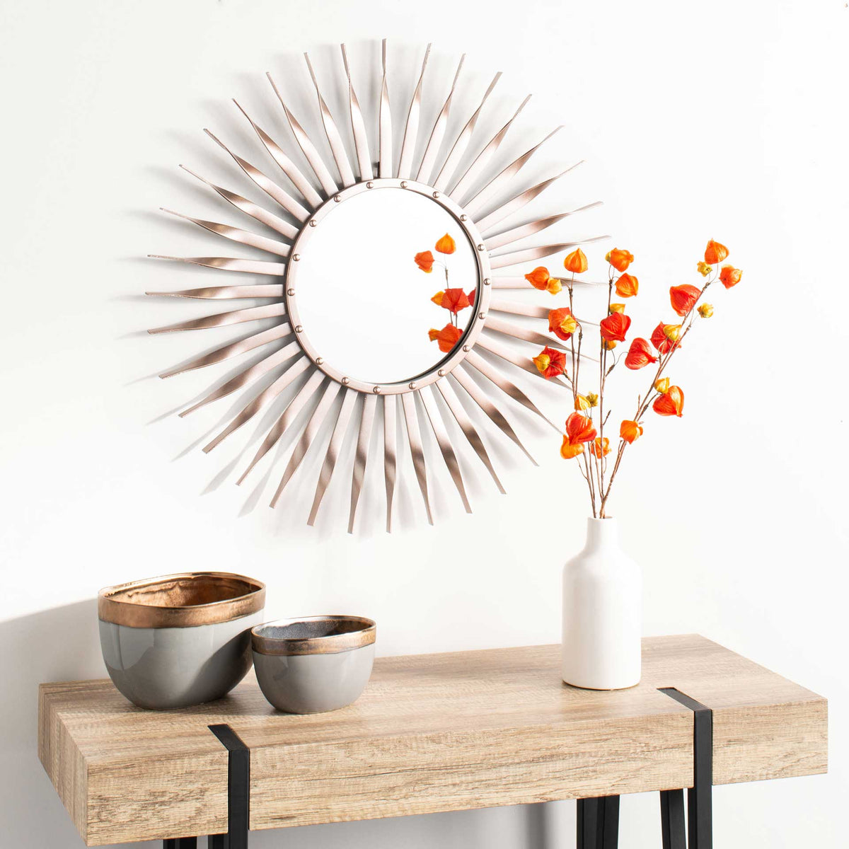 Rose gold sunburst mirror creates a radiant focal point above a natural wood console