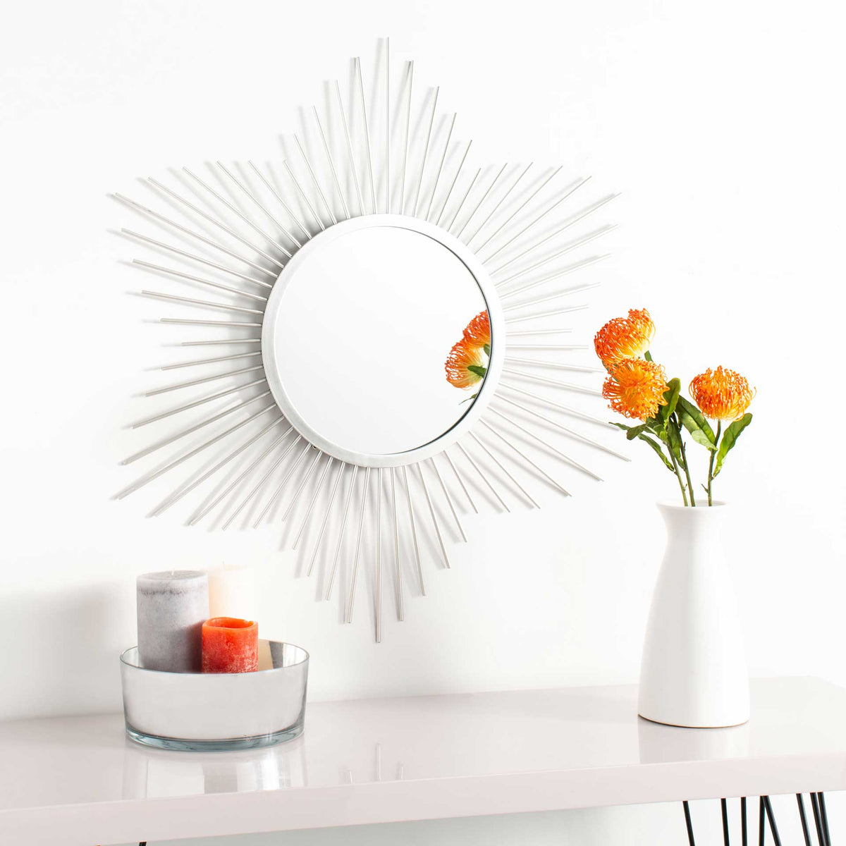 A silver sunburst mirror adds a sculptural accent above a console with its slender, radiating rays.
