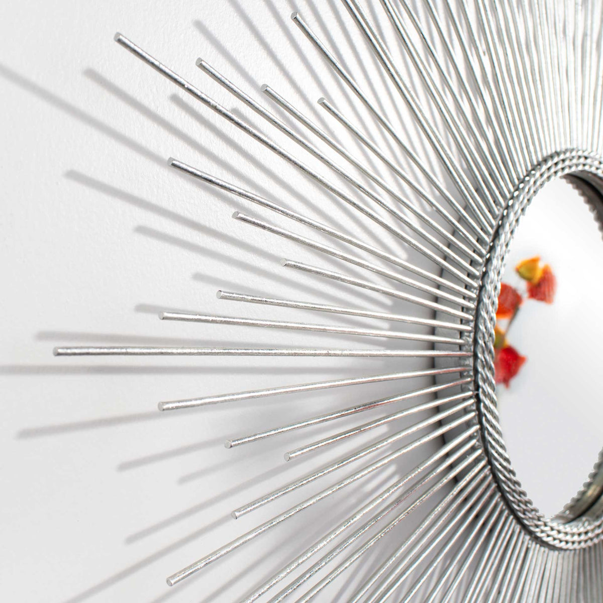 Staggered silver metal rays extend from a textured frame around the mirror