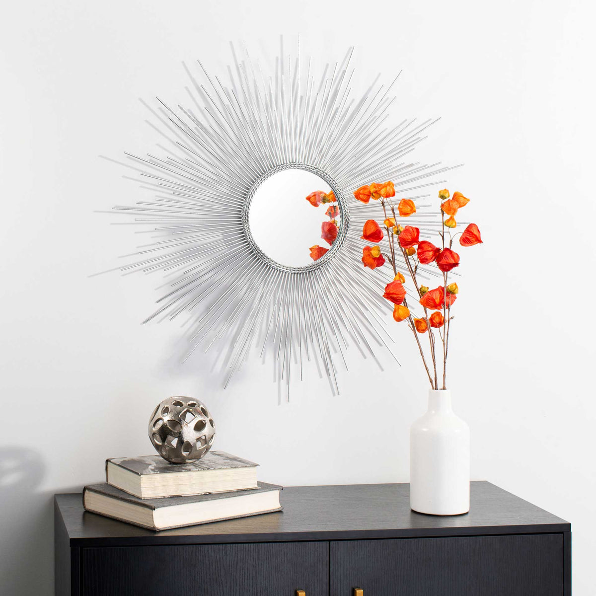 A silver sunburst mirror adds shimmer and texture above a console