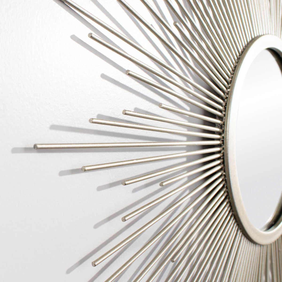 Slender silver metal rays fan out from the mirror's round frame for a sculptural finish