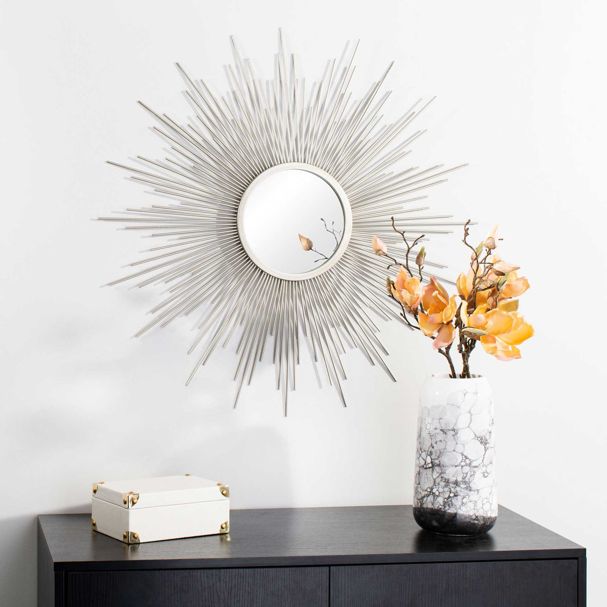 A silver sunburst mirror adds a radiant focal point above a dark console