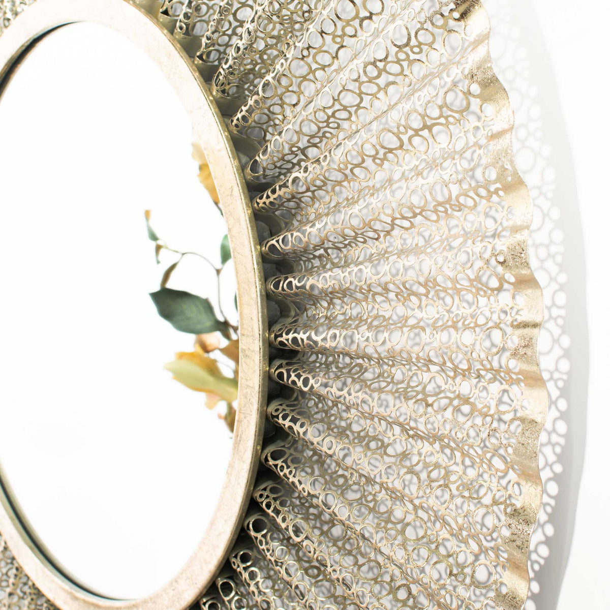 Rippling gold metalwork adds depth and delicate open spaces around the mirror