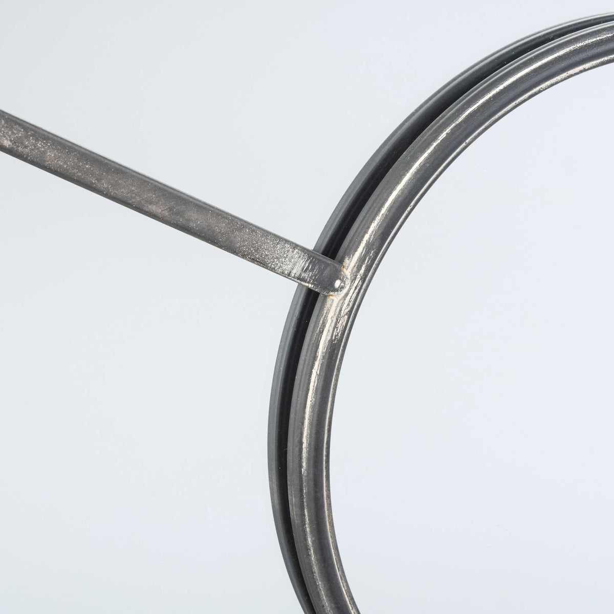 Textured gunmetal bars meet a rounded metal rim, highlighting the mirror's sculptural frame
